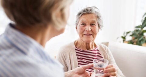 dame âgée prenant un verre d'eau en main